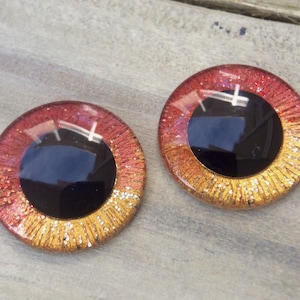 May include: Two round, red, gold, and black plastic eyes with glitter. The eyes are for crafts.