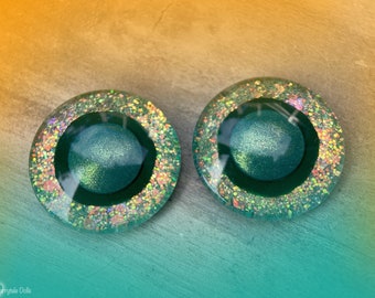 Puede incluir: Dos ojos redondos de resina verde y purpurina iridiscente con pupilas negras. Los ojos tienen un diámetro de aproximadamente 2,5 cm.