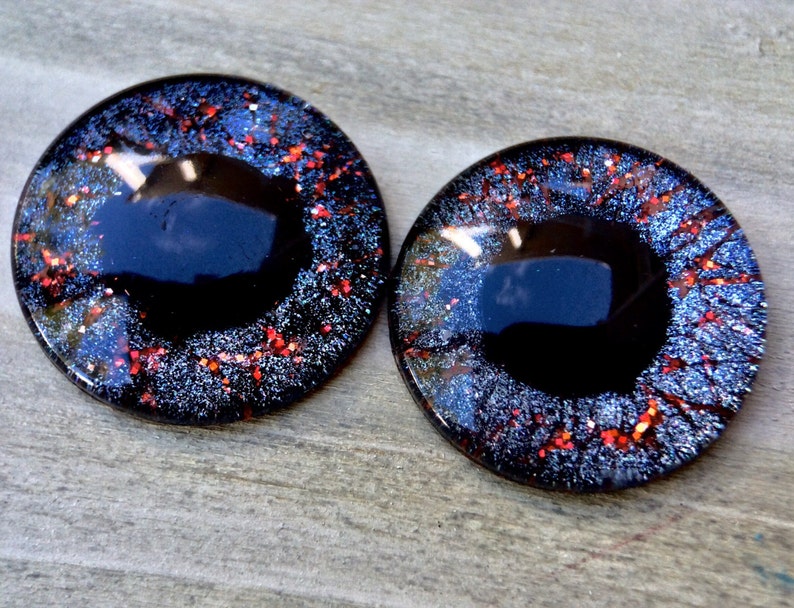 Puede incluir: Dos ojos redondos de pl&aacute;stico negro con detalles de purpurina roja y plateada. Los ojos tienen un di&aacute;metro de aproximadamente 2,5 cm.