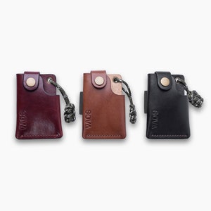 Peut inclure: Trois porte-cl&eacute;s en cuir avec une petite poche et une boucle. Les porte-cl&eacute;s sont bordeaux, marron et noir. Chaque porte-cl&eacute;s porte le mot "SOVA" en relief sur le devant.
