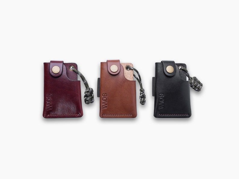 Peut inclure: Trois porte-cl&eacute;s en cuir avec une petite poche et une boucle. Les porte-cl&eacute;s sont bordeaux, marron et noir. Chaque porte-cl&eacute;s porte le mot "SOVA" en relief sur le devant.