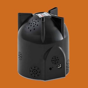 May include: Black speaker with a unique design featuring multiple circular speaker grilles and a power cord on the side. The speaker has a textured surface and a rounded shape.