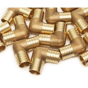 May include: A group of brass elbow pipe fittings with a threaded design. The fittings are arranged in a pile on a white surface.