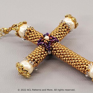 May include: Gold-colored beaded cross pendant necklace. The cross features a detailed design with gold beads, white pearl accents, and a purple beaded center. The necklace has a gold chain.