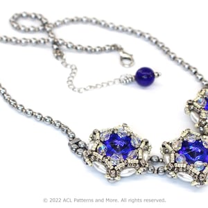 May include: A silver chain necklace with three blue crystal pendant charms. The charms are surrounded by smaller silver beads and white pearls.