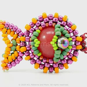 May include: A beaded fish charm with a pink, orange and green colour scheme. The fish has a red stone in the centre and iridescent beads for eyes.
