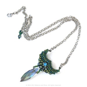 May include: A silver chain necklace with a green and blue beaded pendant. The pendant is shaped like a crescent moon with a teardrop-shaped crystal hanging from the bottom.