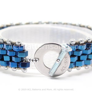May include: A blue and silver beaded bracelet with a metal clasp. The clasp has the text "ACL-Ste" on it.