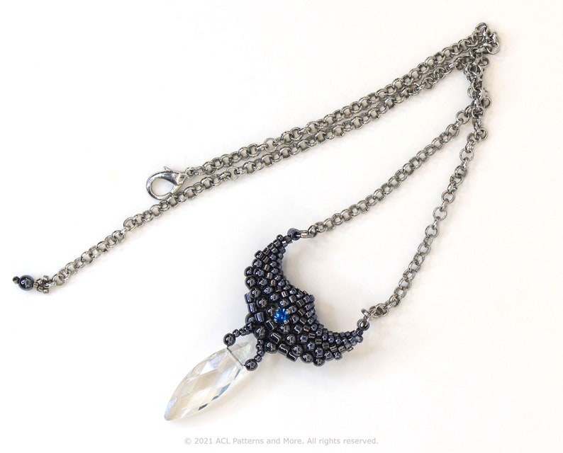 May include: A silver chain necklace with a black and blue beaded pendant featuring a clear crystal drop.