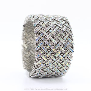 May include: A silver bracelet with a geometric design featuring iridescent rhinestones. The bracelet is made of metal beads and has a woven pattern.