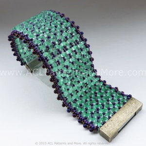 Op de afbeelding: Een groene en paarse kralen armband met een zilveren sluiting. De armband is gemaakt met kleine, ronde kralen en heeft een textuur.