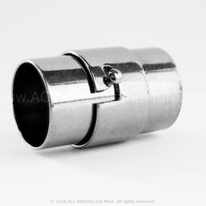 May include: A silver-colored magnetic clasp, designed for jewelry making. The clasp is cylindrical with a secure, interlocking mechanism. The metal has a polished finish, reflecting light. The design is simple and functional, suitable for various jewelry projects.