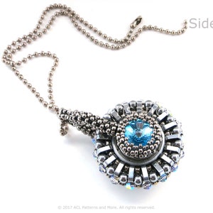 Puede incluir: Un collar de cadena de plata con un colgante que presenta un cristal azul rodeado de cuentas plateadas. El colgante tiene forma de espiral.