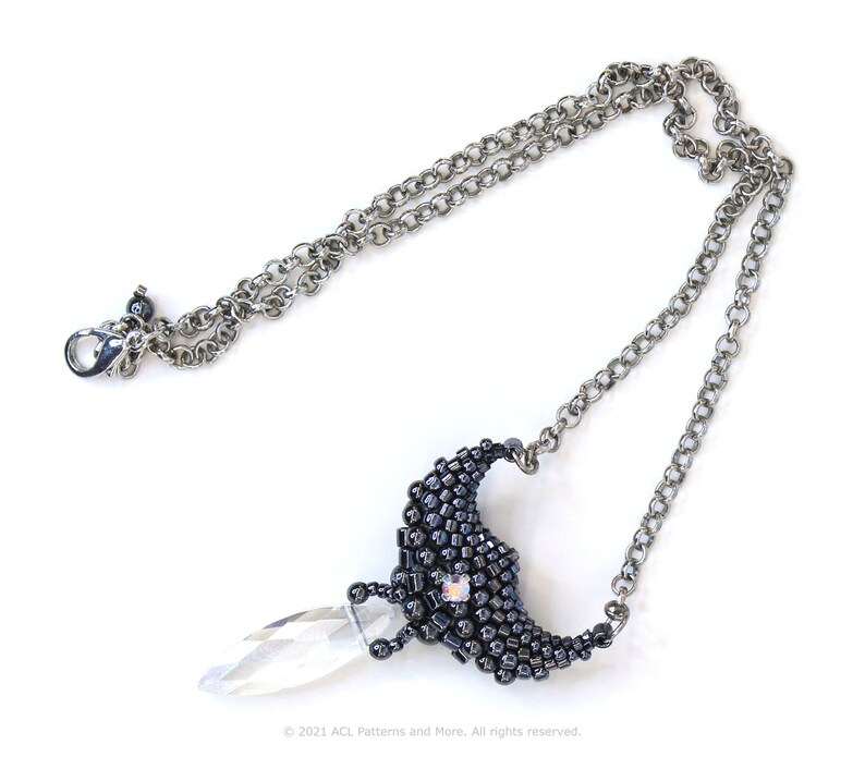 May include: A silver chain necklace with a black beaded crescent moon pendant and a clear crystal teardrop hanging from the bottom.