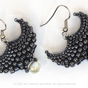 May include: A pair of crescent moon earrings made with black beads and a clear iridescent bead accent. The earrings are silver in color and have a hook closure.