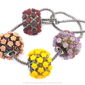 May include: A necklace featuring four beaded floral designs in shades of red, peach, yellow, and purple. The beads are connected by a silver chain. The necklace has a unique, handcrafted appearance.