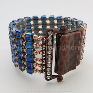 May include: A blue and copper beaded bracelet with a crystal-encrusted clasp. The bracelet is made with small square beads and round beads.