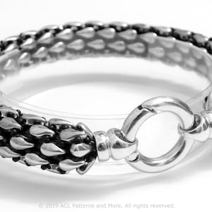 May include: A silver bracelet with a textured, spiky design. The bracelet has a round, open clasp.