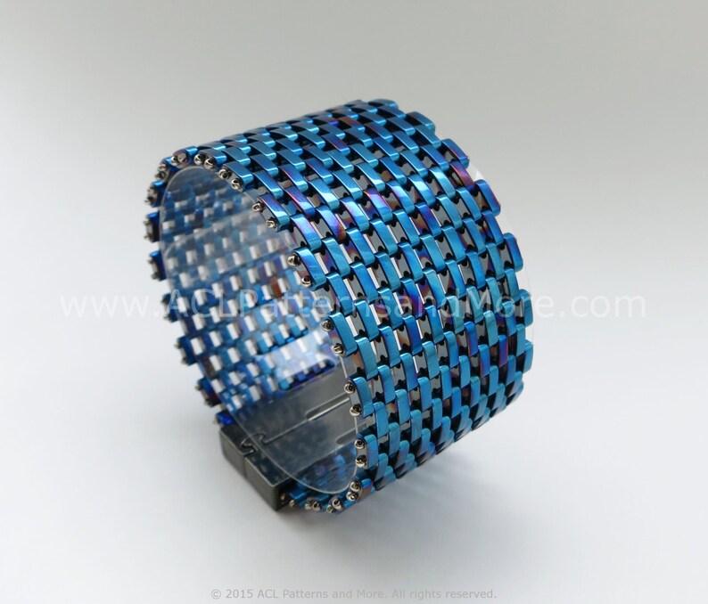 May include: A blue and iridescent metal bracelet with a woven design. The bracelet has a magnetic clasp.