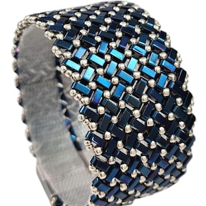 May include: A blue and silver beaded bracelet with a woven pattern. The bracelet is made with small, rectangular beads and round beads.