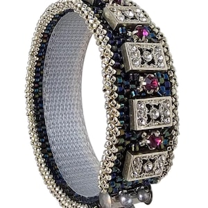 May include: A silver and black beaded bracelet with a row of silver rectangular charms set with clear rhinestones and pink gems.