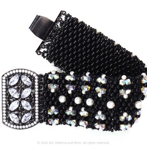 May include: A black beaded bracelet with a silver clasp and crystal accents. The bracelet is made with small black beads and features a decorative silver clasp with clear crystals.