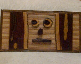 Wood wall art sculpture with geometric oak & pine stained in various colors accenting desert ironwood sections and pieces arrayed as a face.