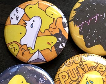May include: Four yellow and black button pins with different designs. One pin features a ghost and yellow chicks, another has a yellow chick with tears, another has a silhouette of a person with the word "グソップ" in pink, and the last pin has a yellow chick with the text "おやすみ" in black.