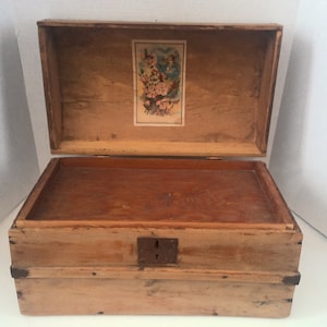 May include: A wooden box with a hinged lid and a lock. The lid is open and the inside of the box is visible. The box is made of light wood and has a floral design on the inside of the lid.