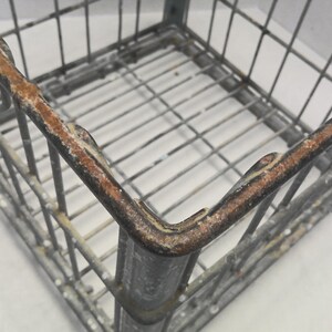 Puede incluir: Una caja de alambre de metal cuadrada con bordes oxidados. La caja est&aacute; hecha de alambre de metal delgado y tiene un acabado gris. La caja est&aacute; vac&iacute;a.