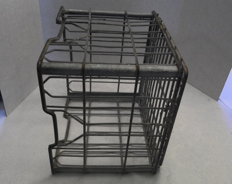 Puede incluir: Una caja de alambre de metal vintage con las palabras "Borden's 56" impresas en el lateral. La caja est&aacute; hecha de metal galvanizado y tiene una forma rectangular.