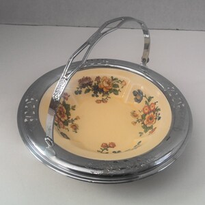 May include: A vintage, silver-plated serving bowl with a floral design. The bowl has a handle and is perfect for serving fruit or snacks.