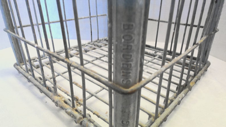 Puede incluir: Una caja de metal vintage con las palabras "BORDENS" en relieve en el lateral. La caja est&aacute; hecha de malla de alambre y tiene una p&aacute;tina oxidada.