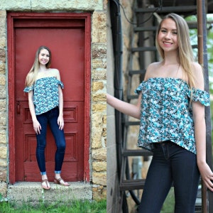 Könnte beinhalten: Eine Frau trägt ein blaues und weißes, blumiges, schulterfreies Oberteil mit Rüschen am Ausschnitt und dunkelblaue Jeans. Sie steht vor einer roten Tür und einer Steinmauer.