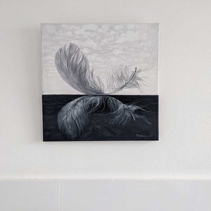 May include: A black and white painting of two feathers, one on top of the other, with a white background on top and a black background on the bottom. The feathers are in a mirrored position, with the top feather pointing to the right and the bottom feather pointing to the left.