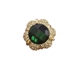 May include: A gold ring with a large, round, faceted green gemstone surrounded by smaller clear gemstones.