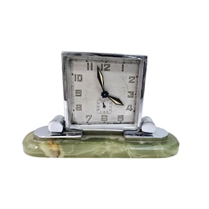 May include: A vintage Art Deco style clock with a square silver-tone face and black hands. The clock face has black numerals and a small seconds dial. The clock sits on a green onyx base with silver-tone accents.