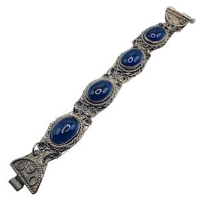 May include: A silver bracelet with four oval-shaped blue stones set in intricate silver filigree. The bracelet has a clasp on one end.