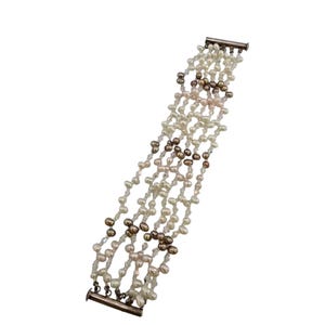 Puede incluir: Una pulsera de múltiples hilos con perlas blancas, rosas y marrones. La pulsera tiene un cierre plateado y está diseñada con múltiples hilos de perlas entrelazadas, creando un aspecto delicado y elegante.