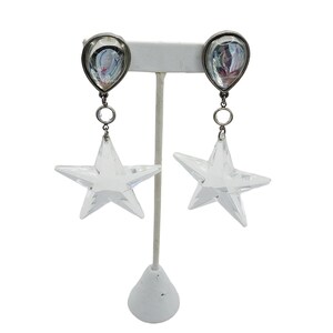 May include: A pair of silver tone earrings with clear crystal star charms and teardrop shaped crystal accents.