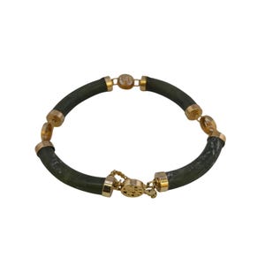 May include: A jade bracelet with gold-colored accents. The bracelet features dark green, curved jade segments connected by gold-toned metal links. The clasp and connecting elements are also gold-colored.