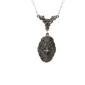 Puede incluir: Un collar con colgante plateado con un dise&ntilde;o de filigrana ornamentado. El colgante tiene forma ovalada con una piedra central similar a un diamante. El collar tiene una cadena delicada y una parte superior intrincada de inspiraci&oacute;n floral.