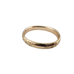 Può includere: Un braccialetto rigido in oro con un design floreale.