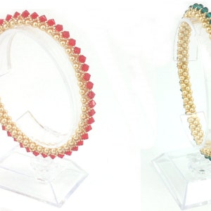 May include: Two beaded bracelets on display stands. The bracelet on the left is red and gold, while the bracelet on the right is green and gold.
