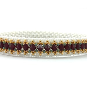 May include: A white beaded bracelet with a band of maroon and gold beads.