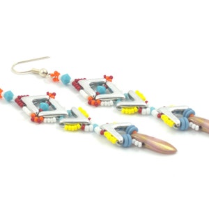 May include: A pair of long, colorful beaded earrings with silver geometric shapes and a teardrop-shaped pendant. The earrings feature a mix of red, white, blue, yellow, and orange beads.