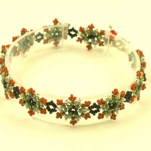 Pode incluir: Um bracelete de contas com um padrão repetitivo de pequenas flores multicoloridas. O bracelete é feito com contas pretas, marrons, prateadas, verdes e brancas.