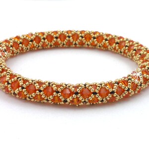 May include: A beaded bracelet with a geometric pattern in orange and gold.
