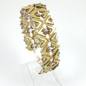 May include: Gold and clear beaded bracelet with a geometric chevron pattern.