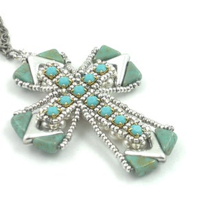 May include: A silver chain necklace with a turquoise and silver cross pendant. The cross is made of small turquoise stones and silver beads.